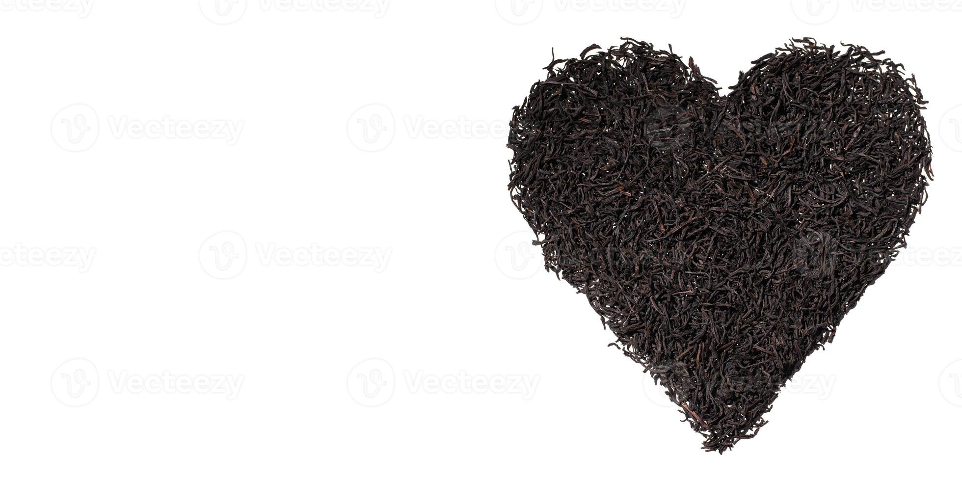 Dry black tea leaves in the shape of heart isolated on white background. Creative banner love for tea. Top view, copy space photo
