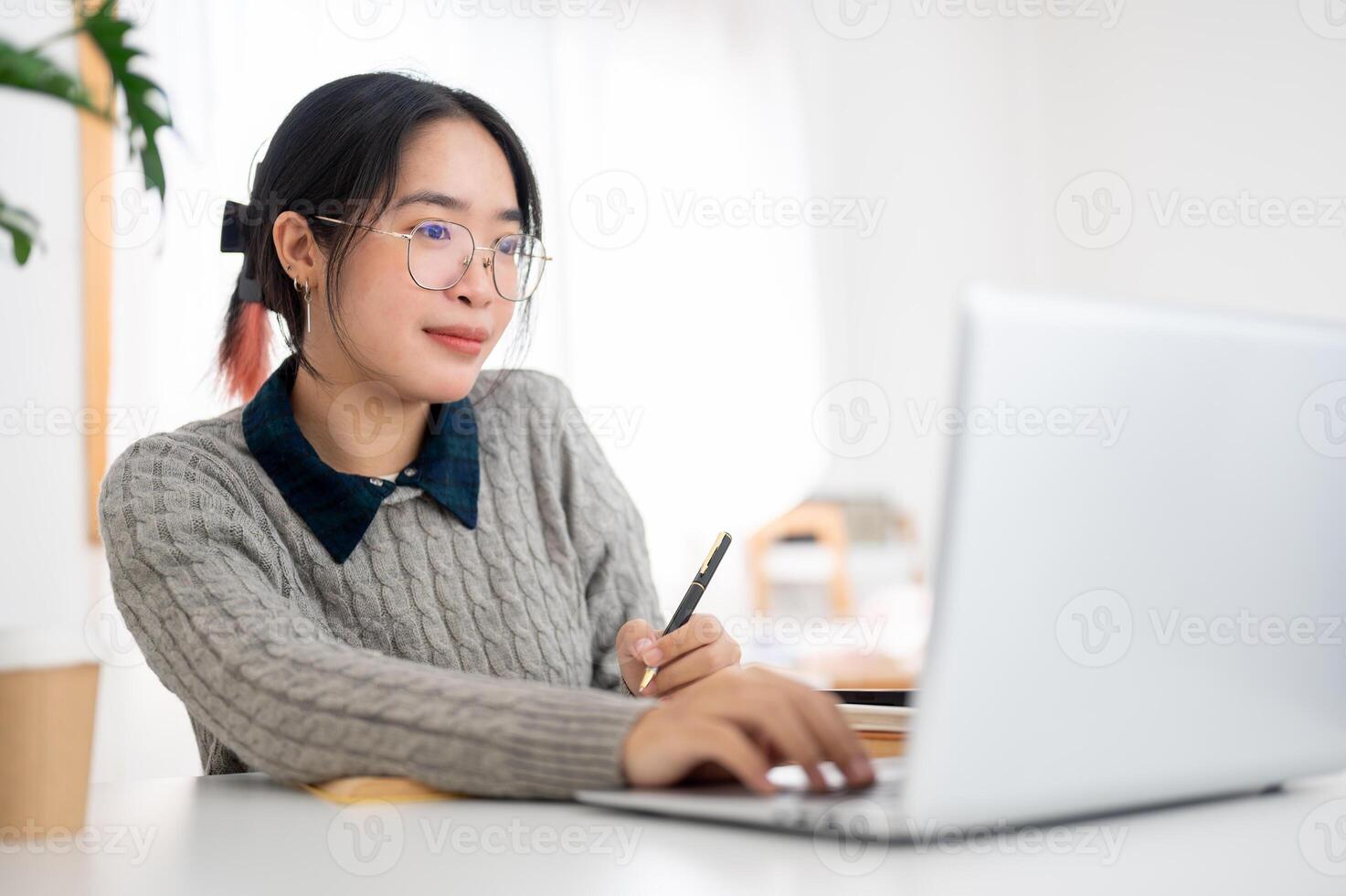 A female college student is focusing on her homework on her laptop in a cafe co-working space. photo