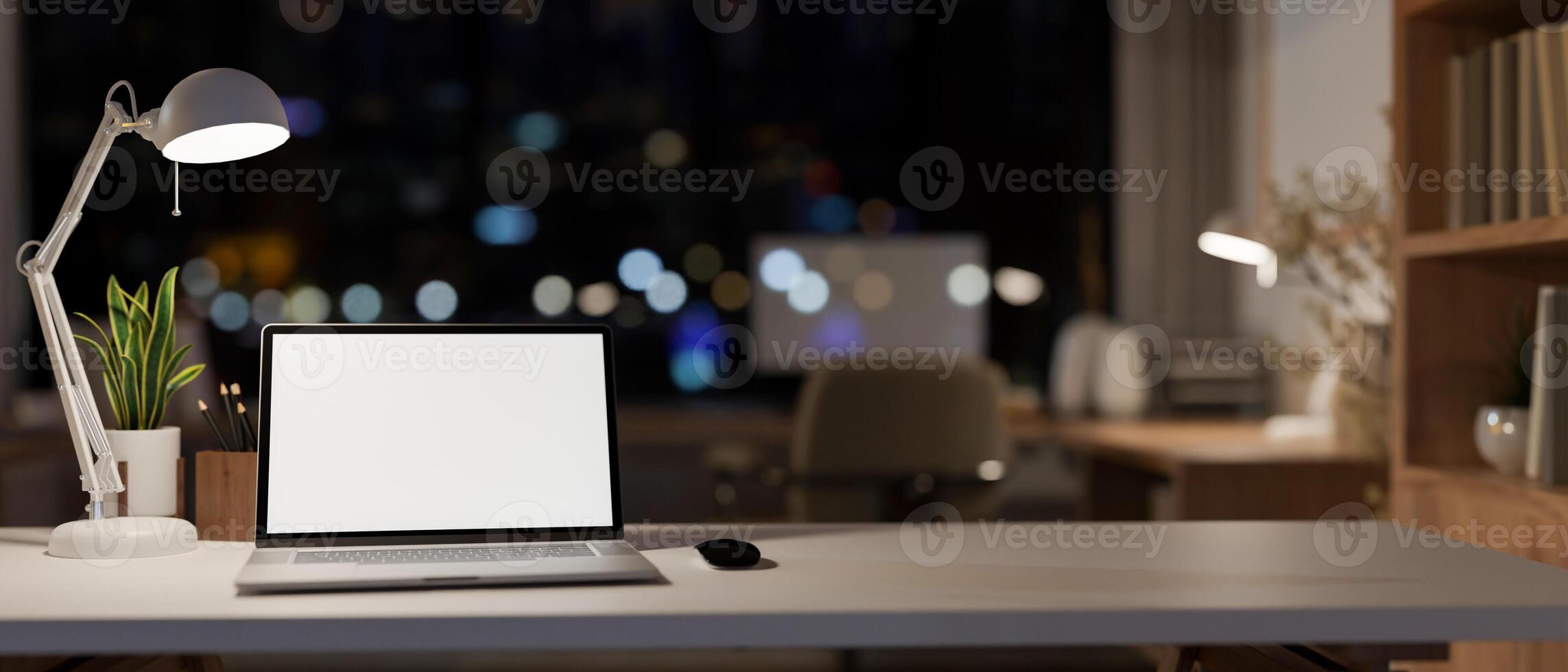 An office desk features a laptop computer mockup in a modern skyscraper office at night. photo