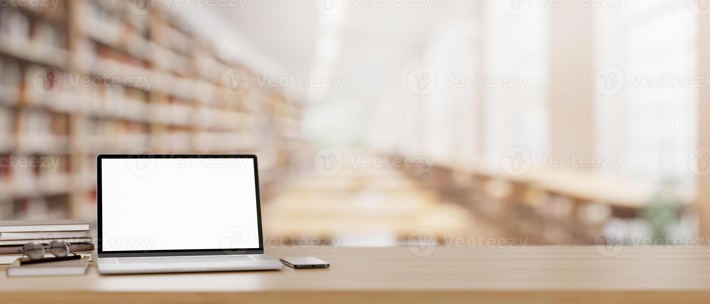 A laptop computer mockup and books on a wooden table in a modern library. photo