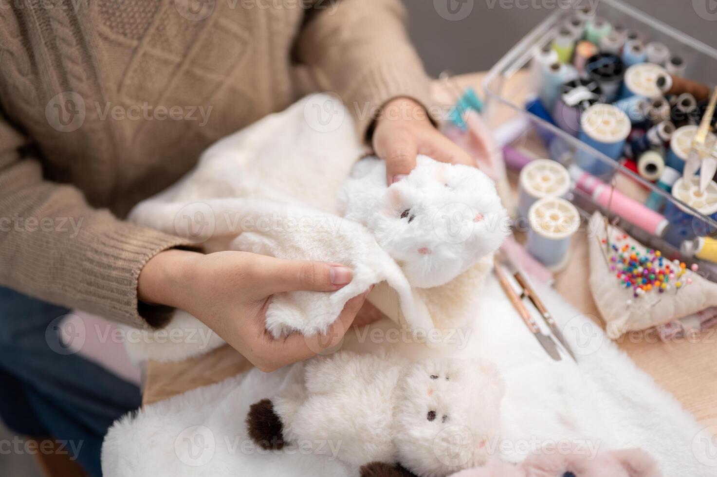 A close-up image of a woman crafting a fluffy plush toy by hand at home. photo