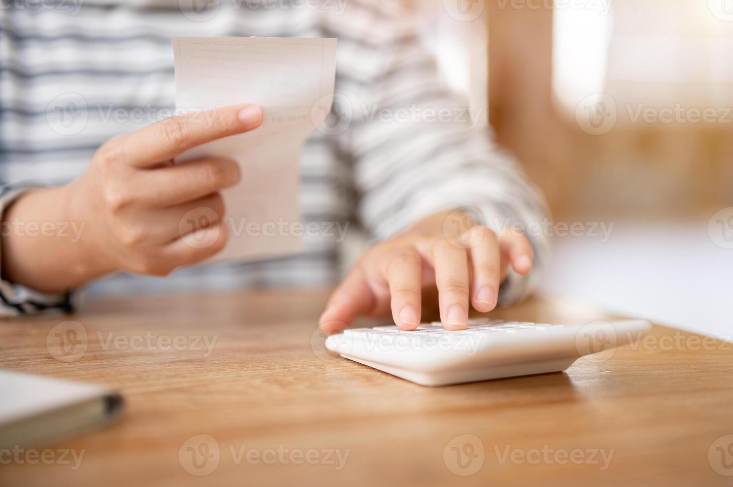 un mujer utilizando un calculadora a un mesa, calculador su casa gastos y facturas. foto