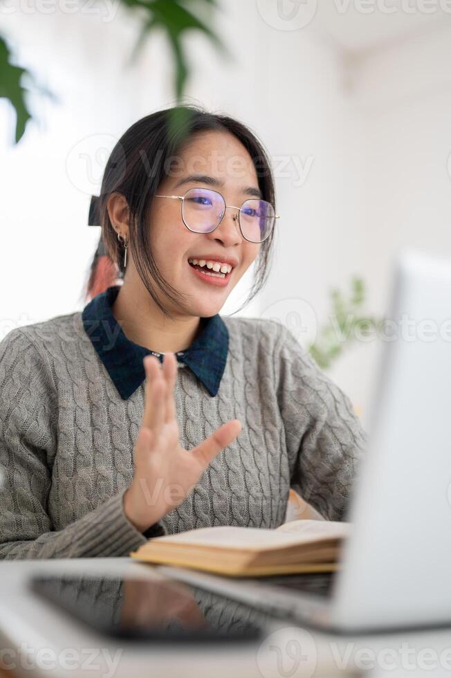 A confident Asian female student is participating in an online class, studying online. photo