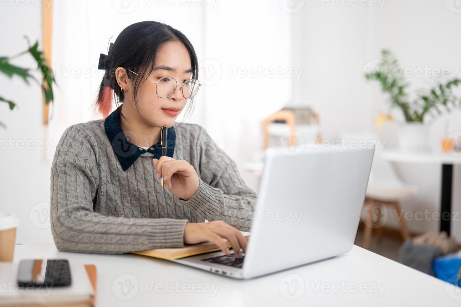 A female college student is focusing on her homework on her laptop in a cafe co-working space. photo