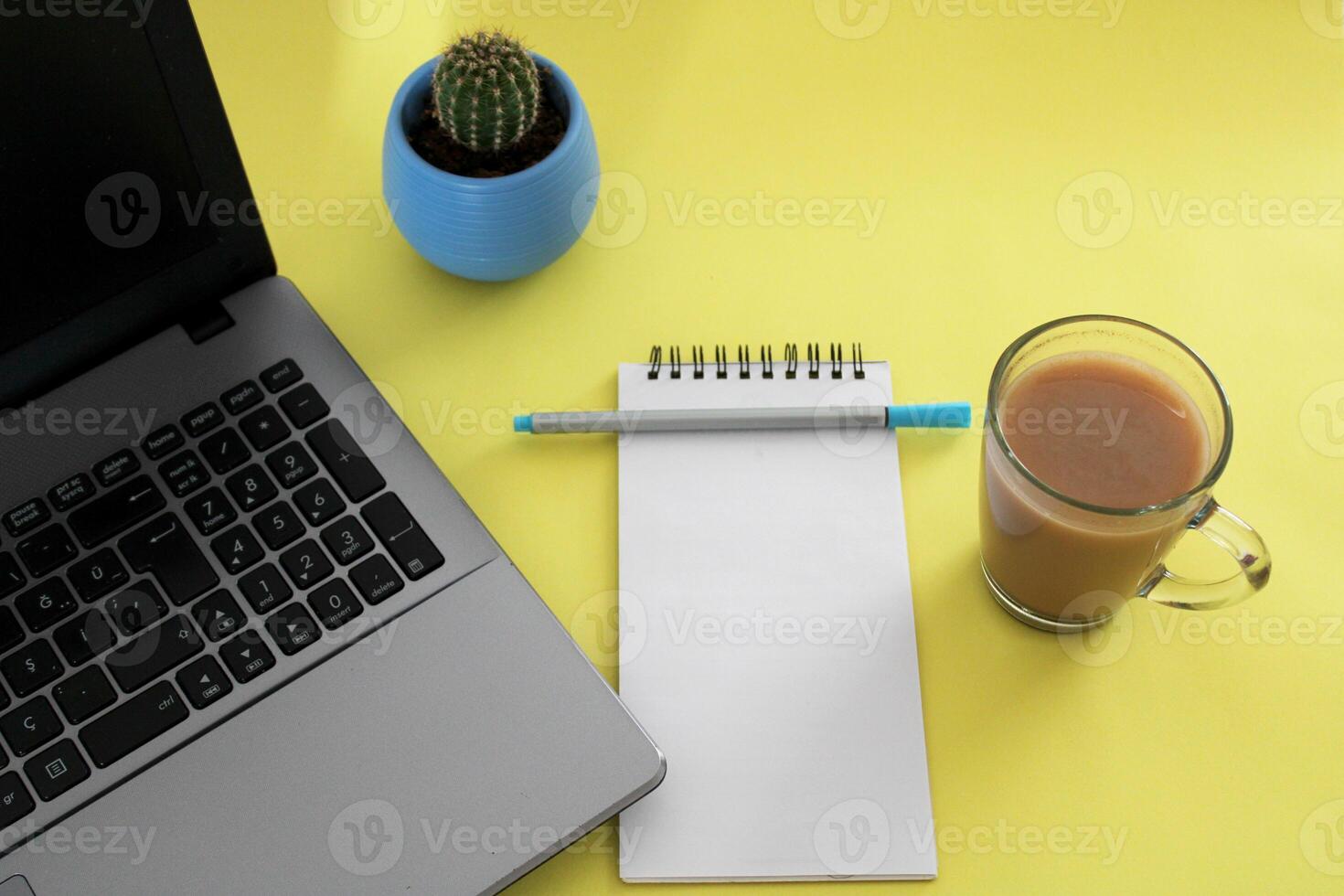 Blank notebook with pen are on top of wood office desk table with a cup of coffee and office supplies, top view. photo