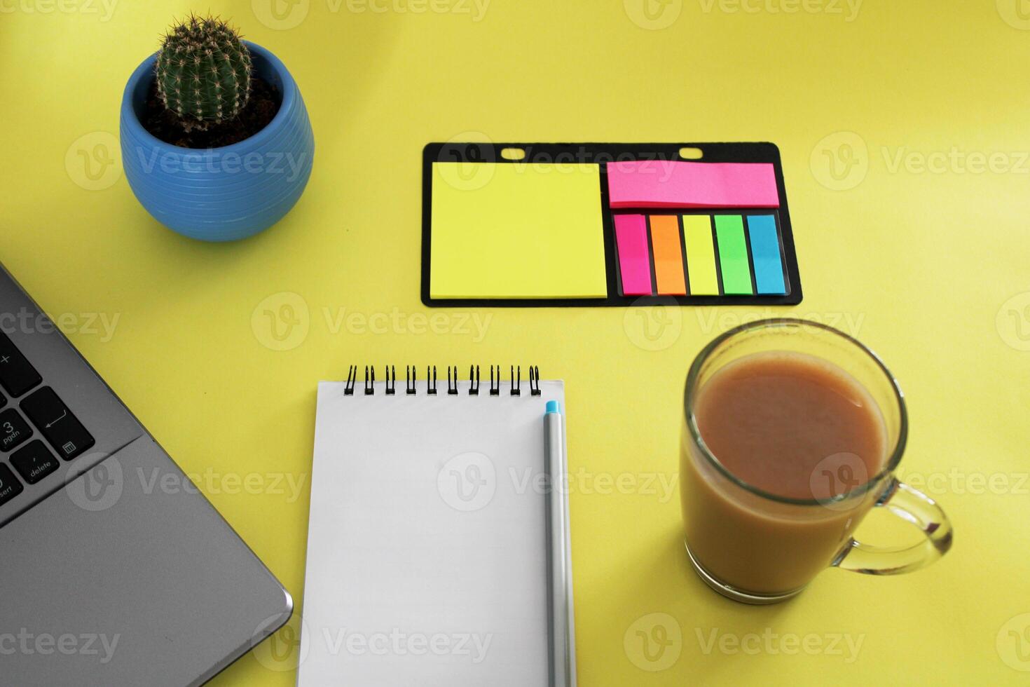 Blank notebook with pen are on top of wood office desk table with a cup of coffee and office supplies, top view. photo