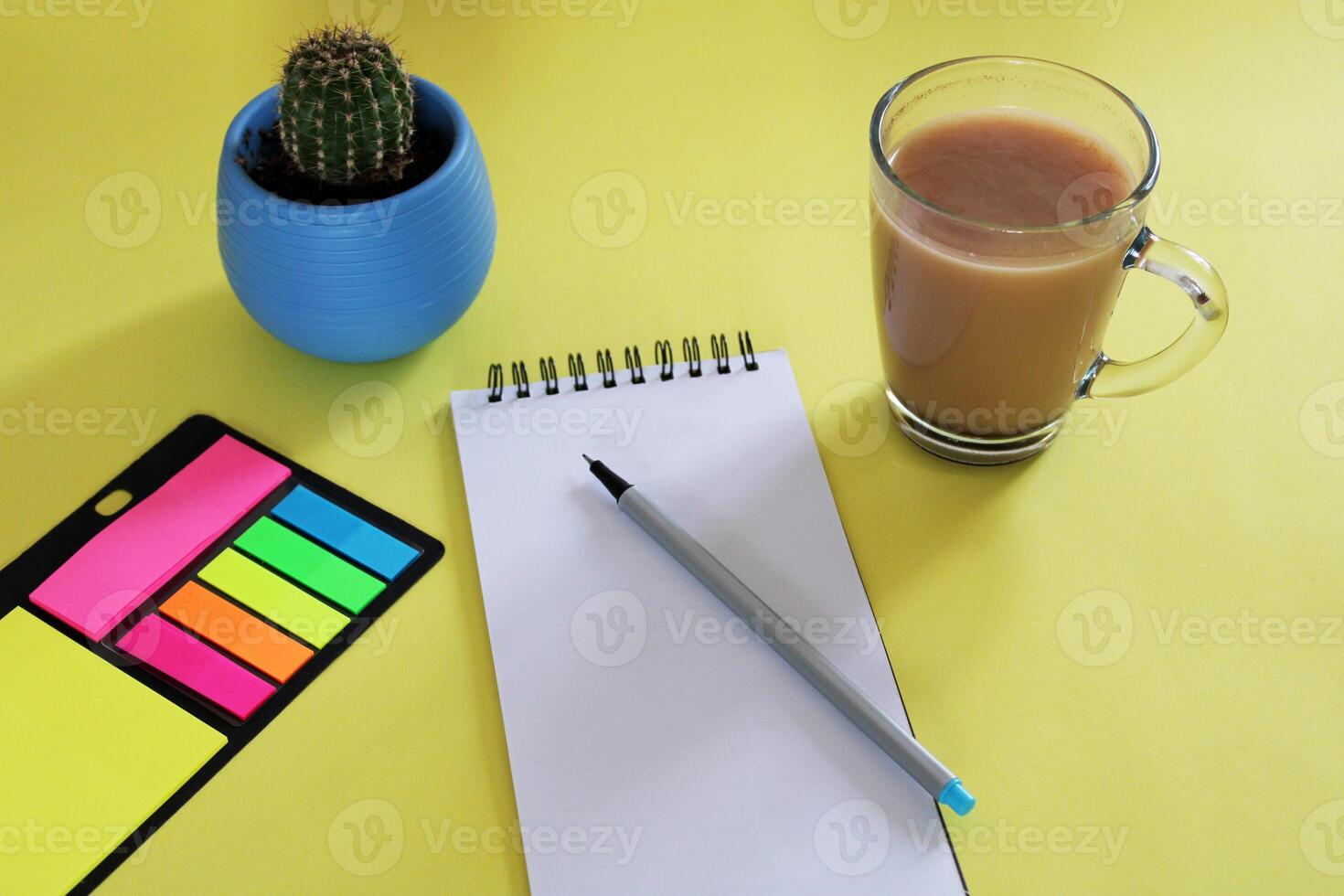 Blank notebook with pen are on top of wood office desk table with a cup of coffee and office supplies, top view. photo
