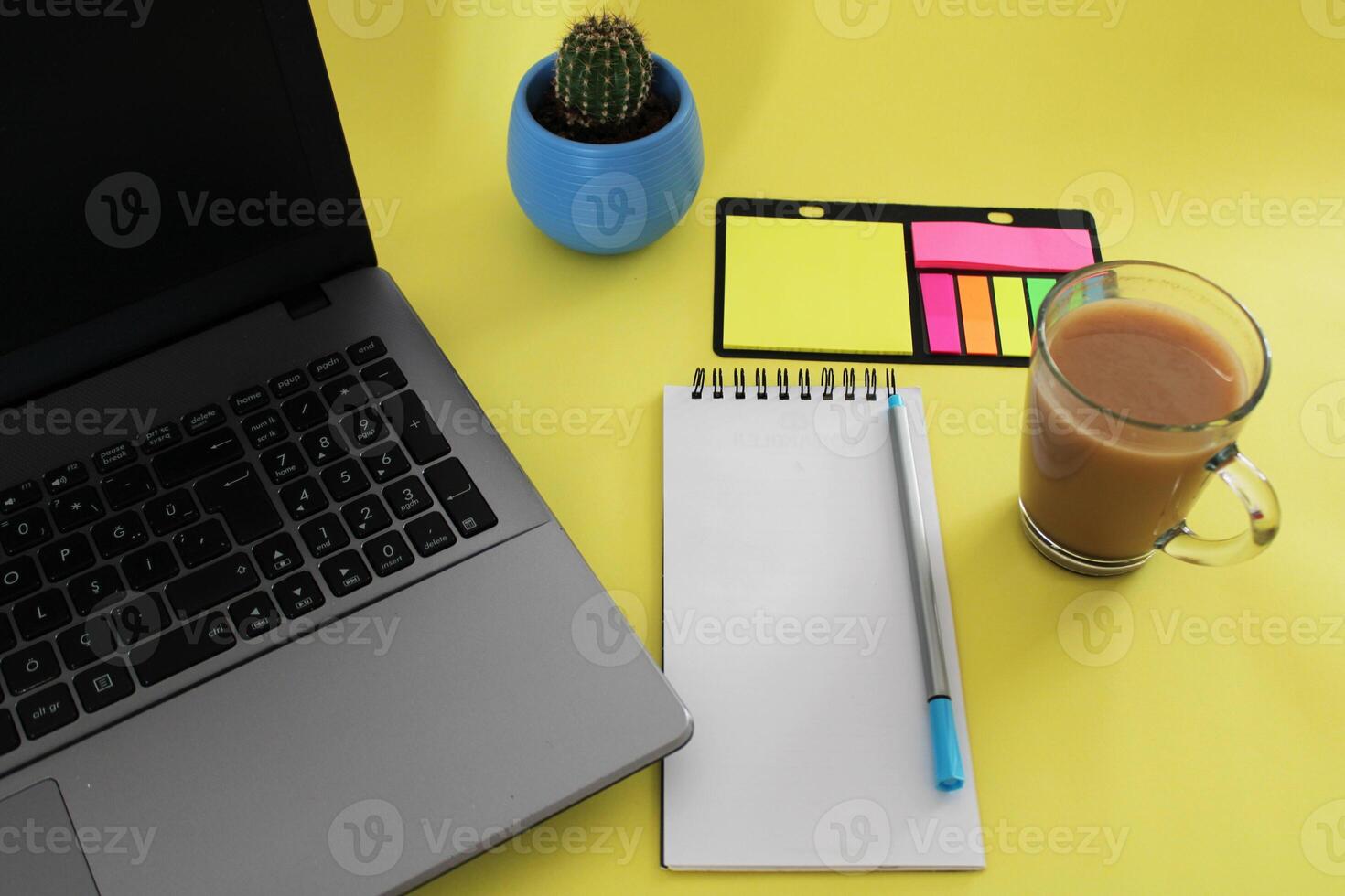 Blank notebook with pen are on top of wood office desk table with a cup of coffee and office supplies, top view. photo
