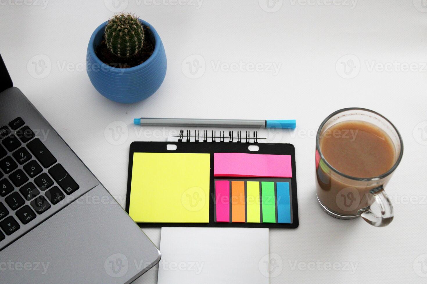 Blank notebook with pen are on top of wood office desk table with a cup of coffee and office supplies, top view. photo