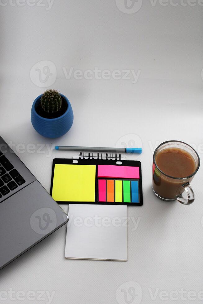 Blank notebook with pen are on top of wood office desk table with a cup of coffee and office supplies, top view. photo