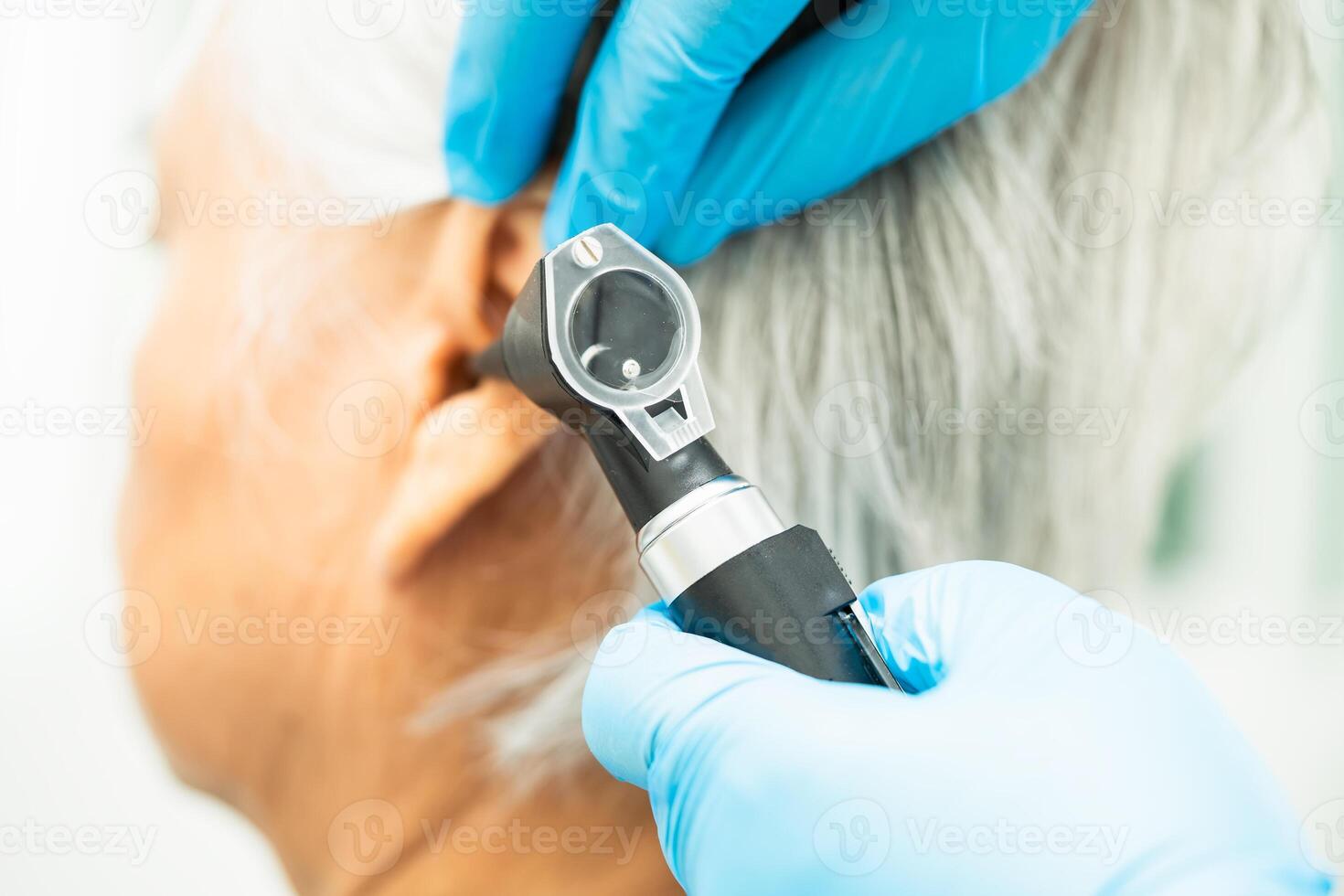 Audiologist or ENT doctor use otoscope checking ear of asian senior woman patient treating hearing loss problem. photo