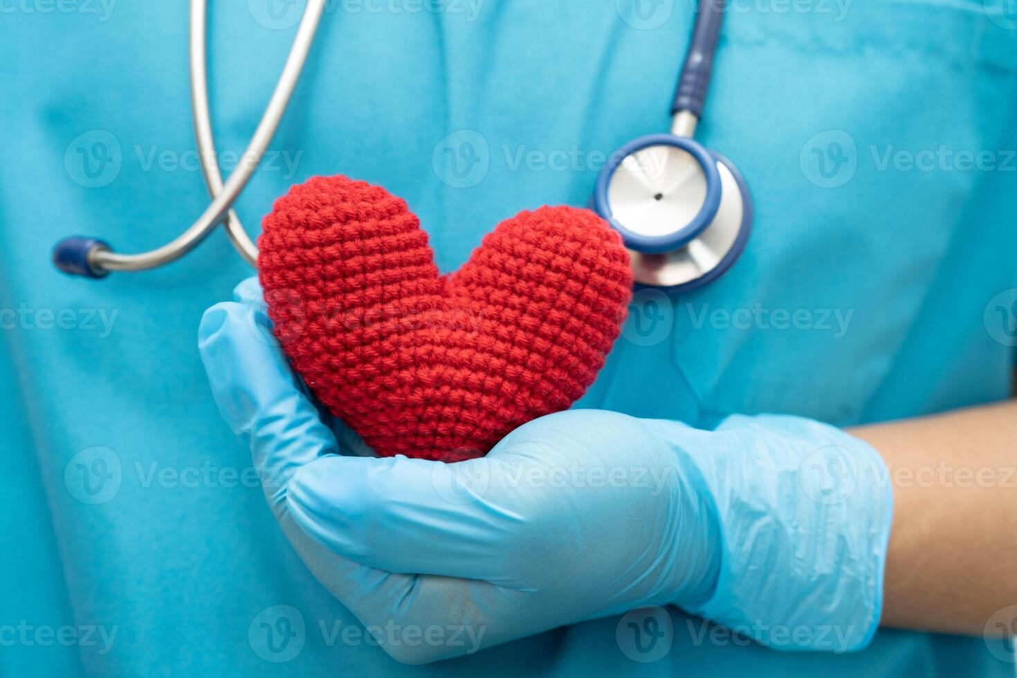 Doctor holding a red heart in hospital ward, healthy strong medical concept. photo