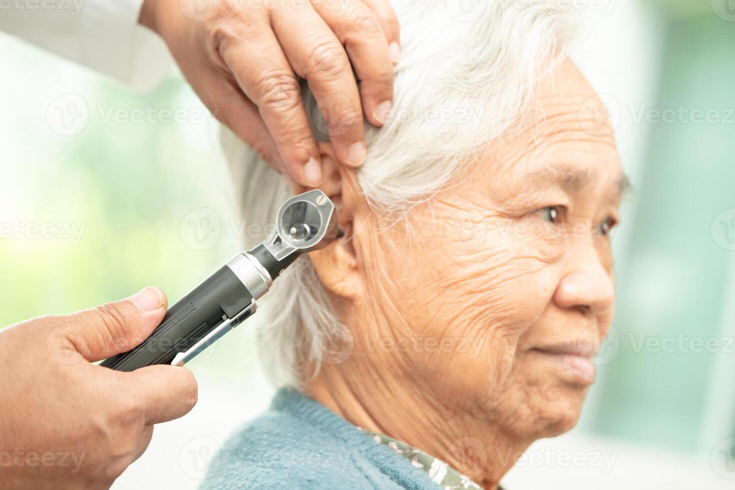 audiólogo o ent médico utilizar otoscopio comprobación oído de asiático mayor mujer paciente tratando escuchando pérdida problema. foto