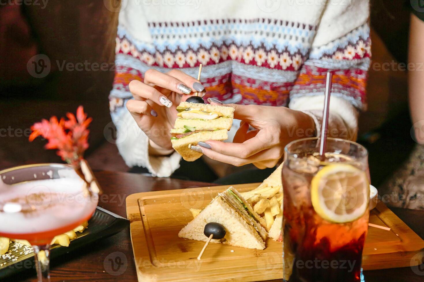 Woman Eating Sandwich and Drinking Drink at Outdoor Cafe photo