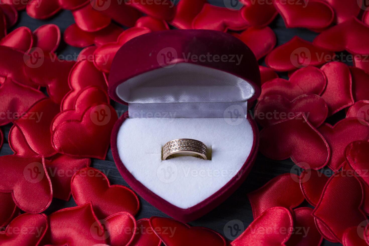 Engagement ring in a red box on a love hearts background. photo