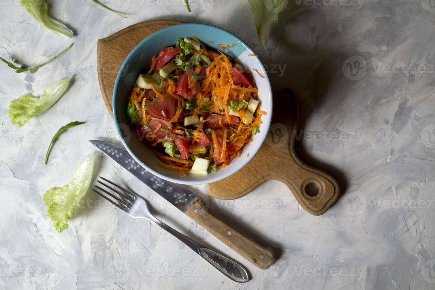 The bowl of organic salad and cutlery on a table. photo