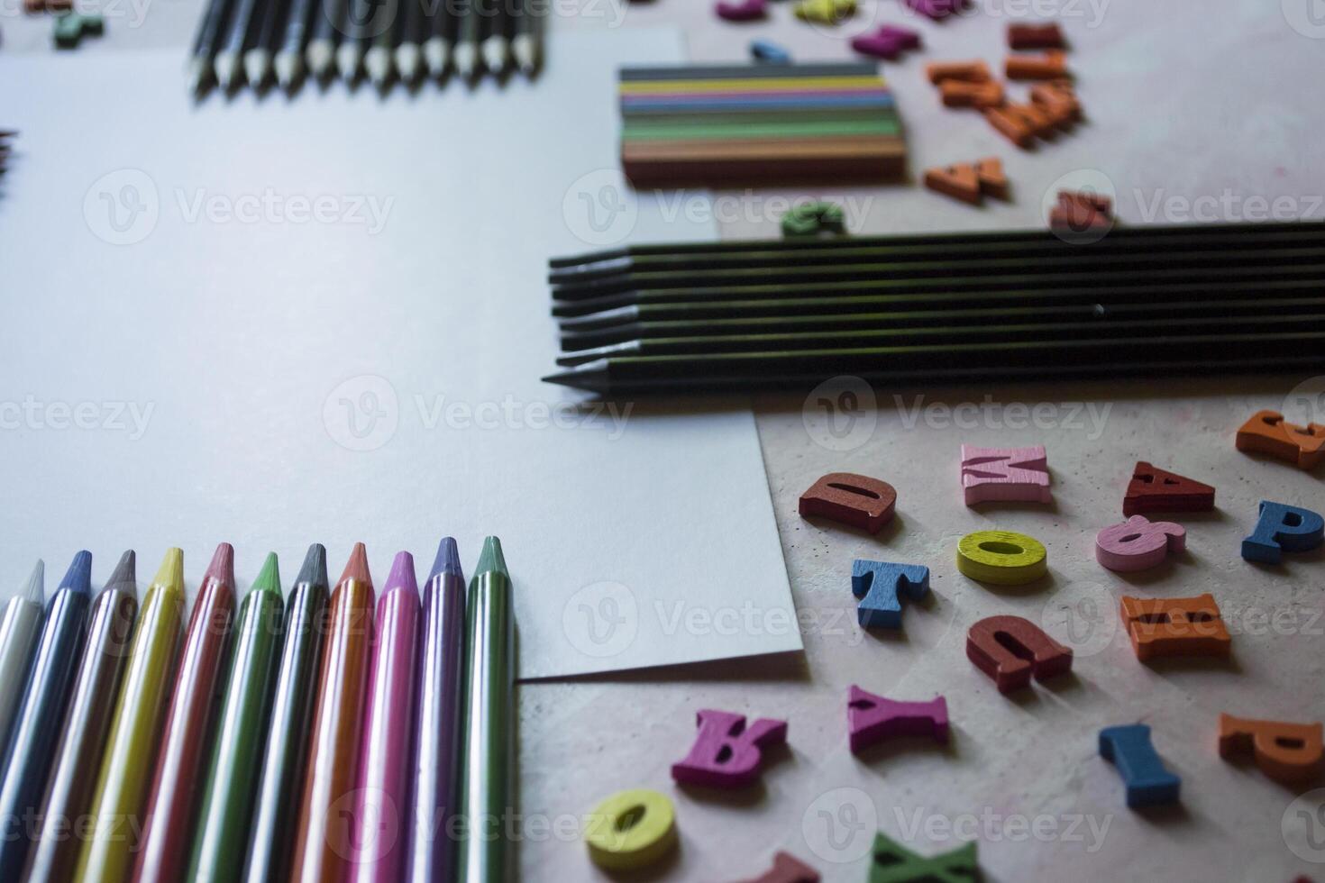 Multicolor letters and set of pencils on the table. Colorful wooden alphabet and pencils on a table. photo