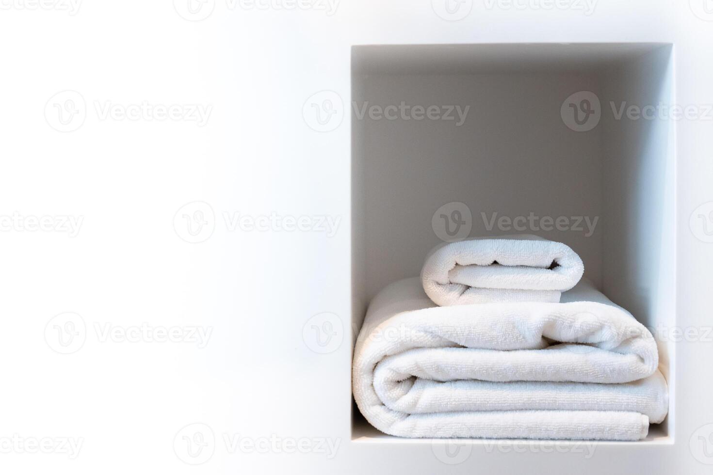 White towel set folded stack in a clean storage simple shelf evoking a sense of calm spa and wellness in a fitness shower, bathroom, laundry or luxury hotel photo