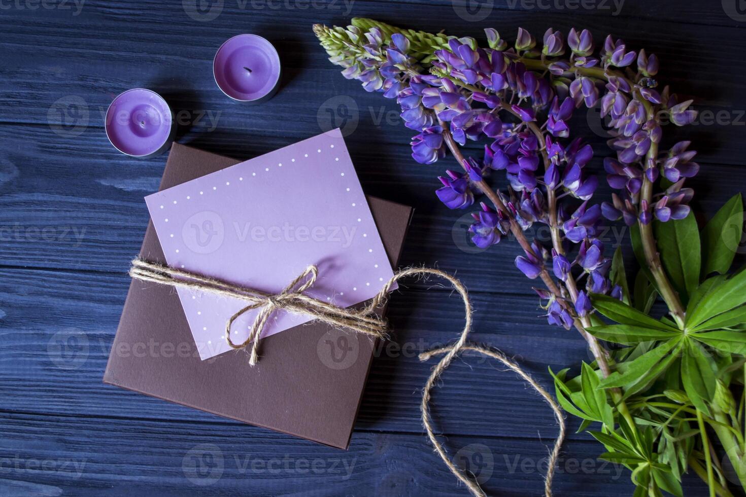 regalo caja con saludo tarjeta y ramo de flores de altramuces en un oscuro azul de madera antecedentes. foto