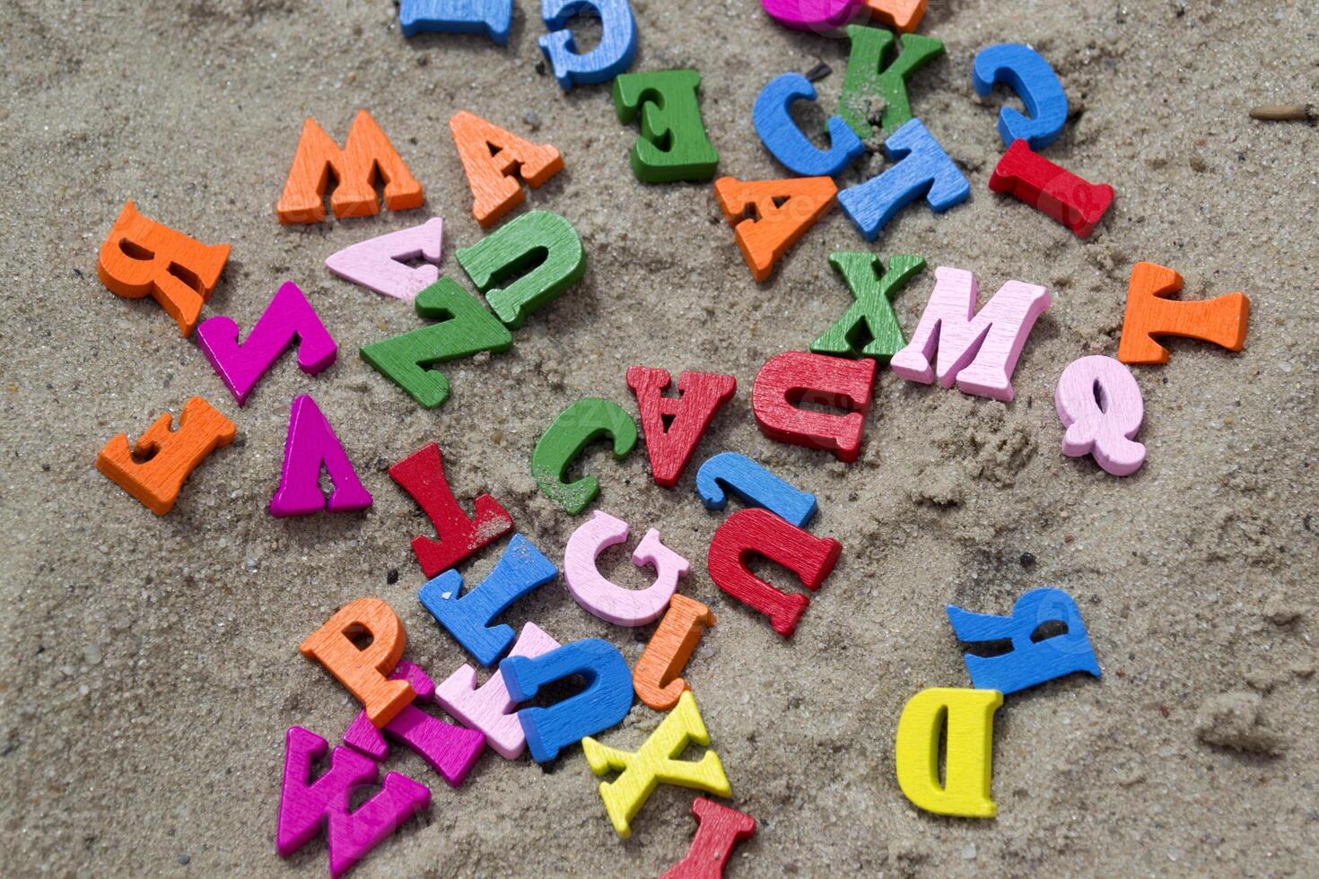 Multicolor wooden letters on a sand close up. photo