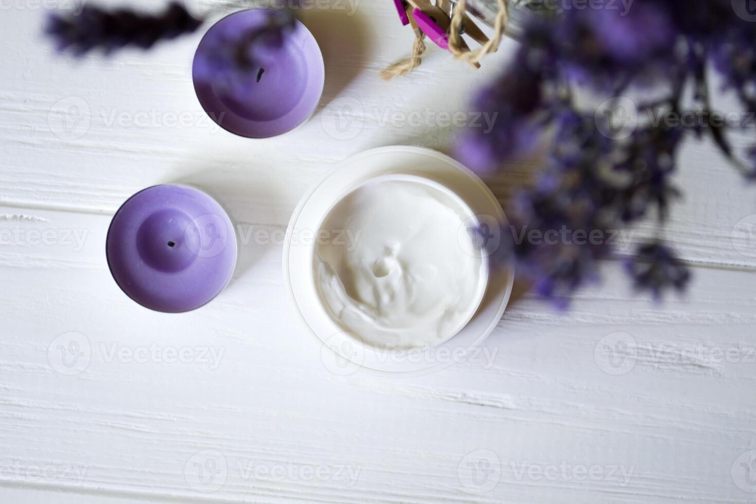 Lavender flowers, candles and cream on a white wooden background. Beauty care. Top view. photo