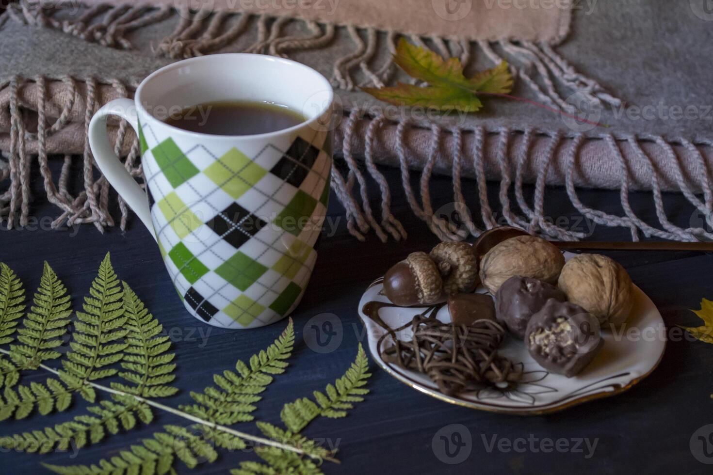 A cup of tea and sweet snacks with decoration by autumn leaves on the blue wooden background. Seasonal still life. photo