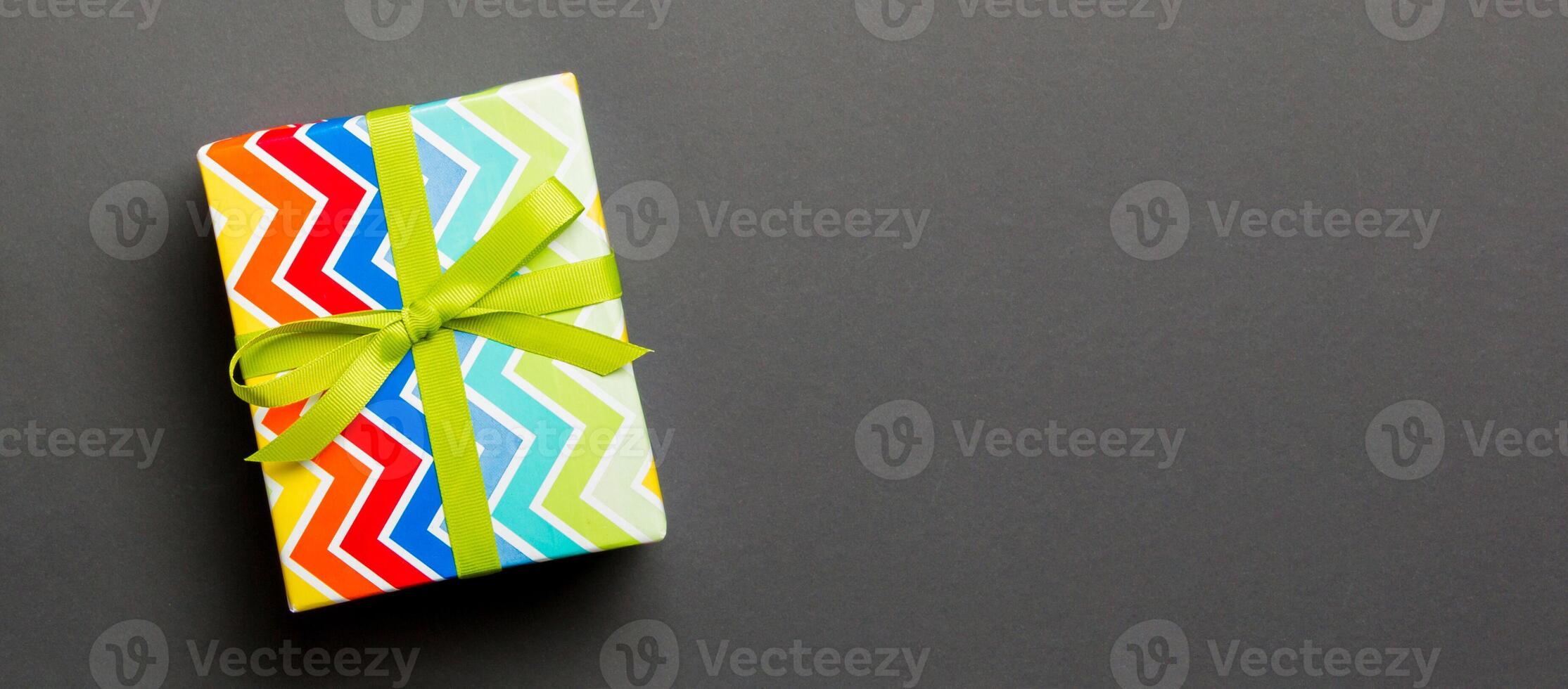 Top view Christmas present box with green bow on black background with copy space photo