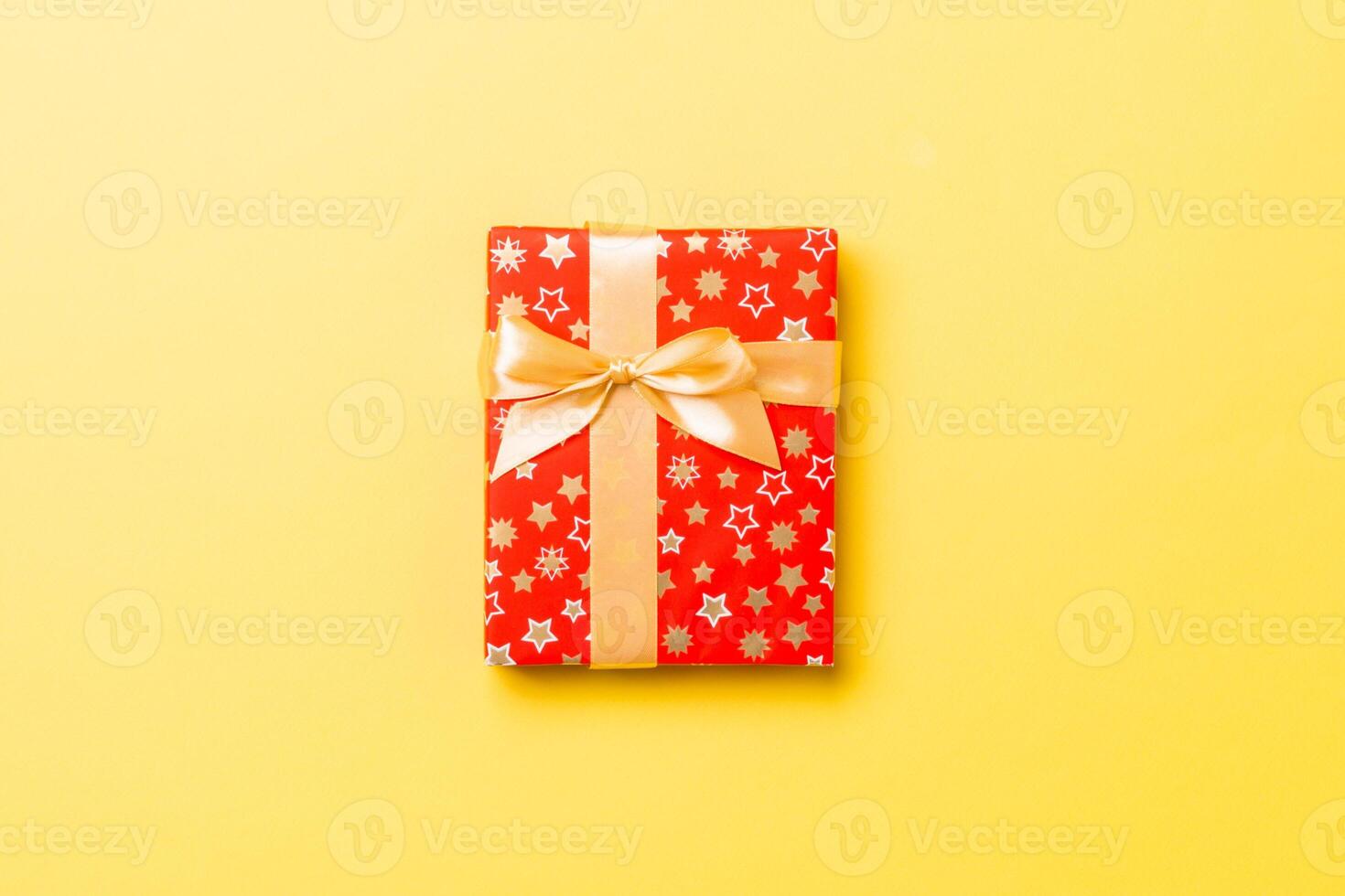 Top view Christmas present box with gold bow on yellow background with copy space photo