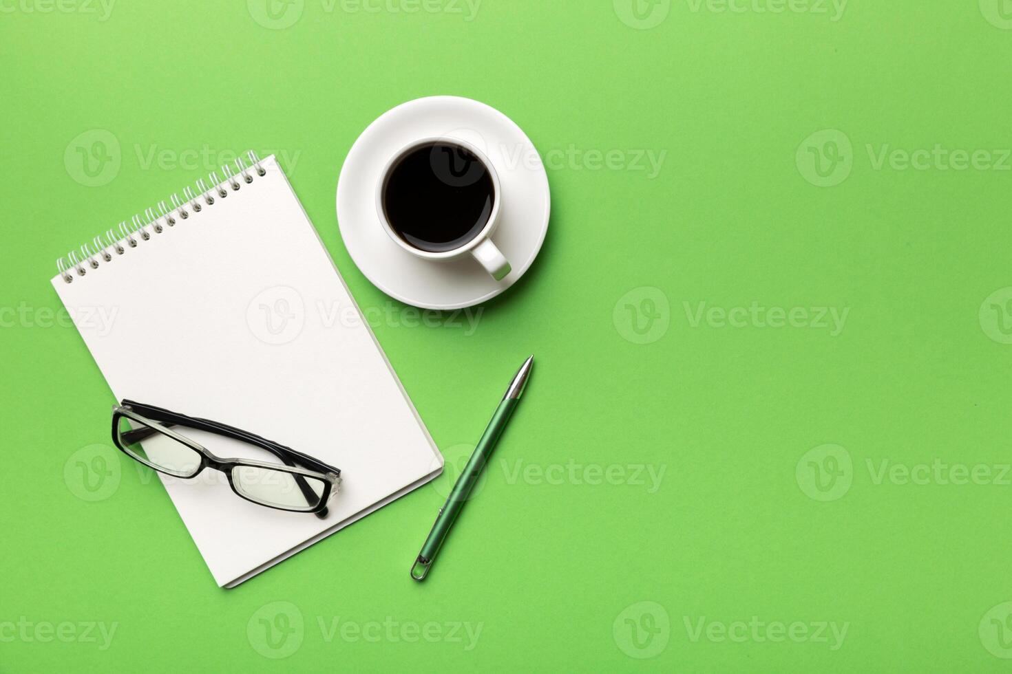 Modern office desk table with notebook and other supplies with cup of coffee. Blank notebook page for you design. Top view, flat lay photo