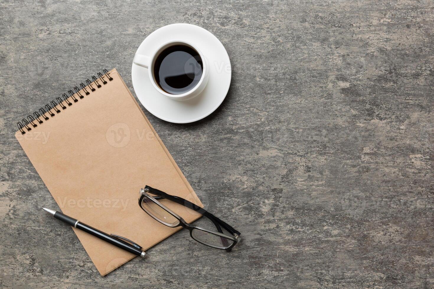 Modern office desk table with notebook and other supplies with cup of coffee. Blank notebook page for you design. Top view, flat lay photo