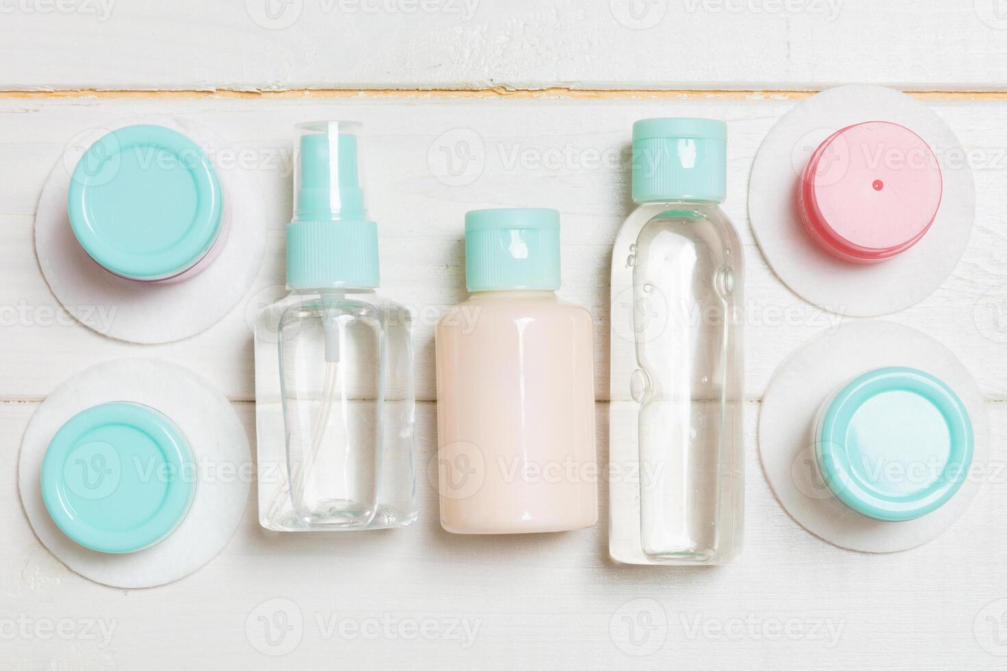 Set of travel size cosmetic bottles on white wooden background. Flat lay of cream jars. Top view of bodycare style concept photo