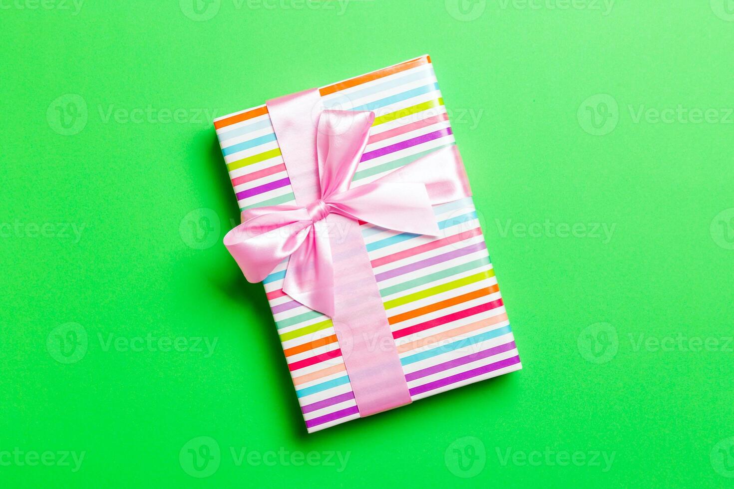 Top view Christmas present box with pink bow on green background with copy space photo