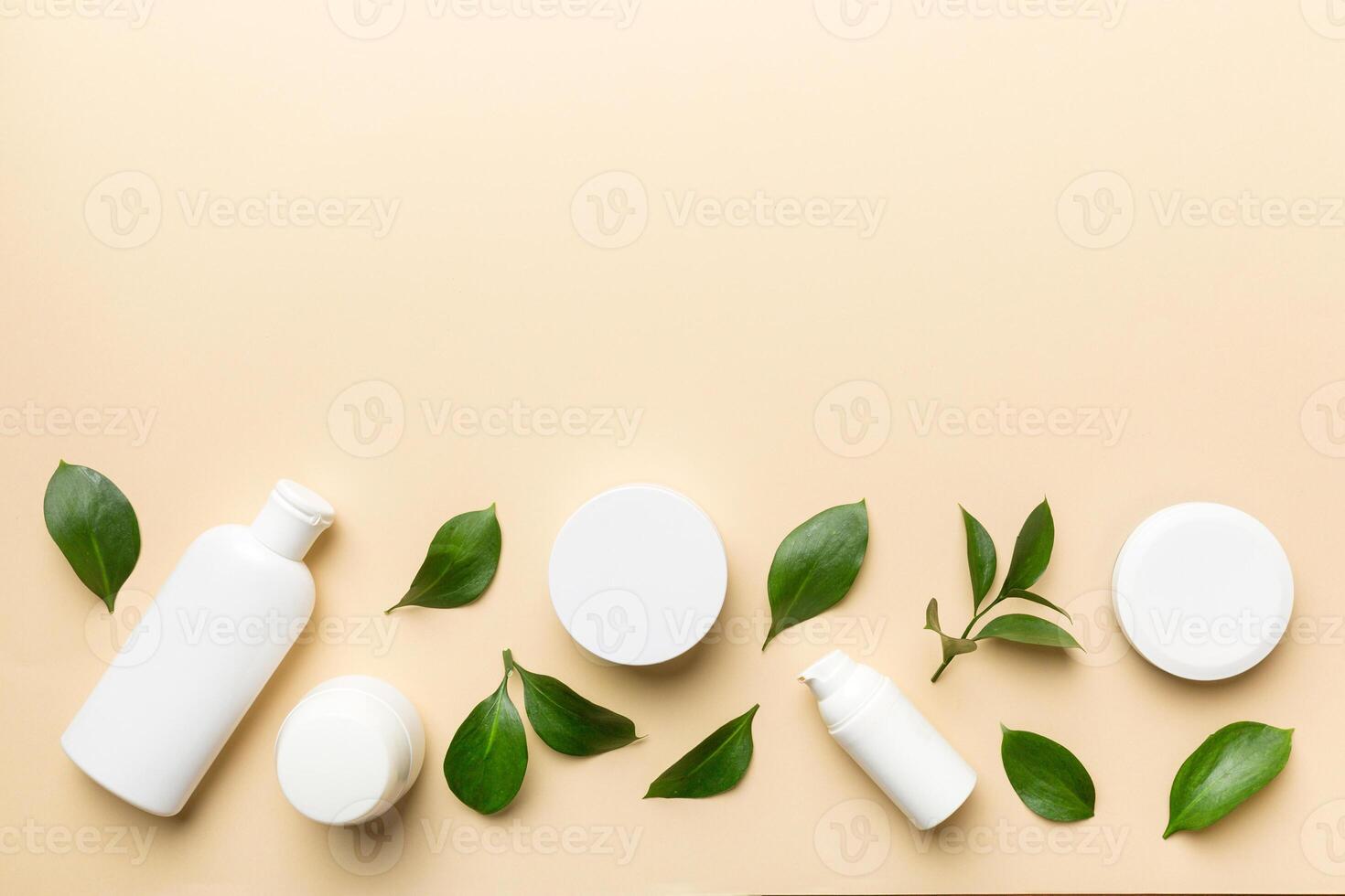 Organic cosmetic products with green leaves on color background. Copy space, flat lay photo