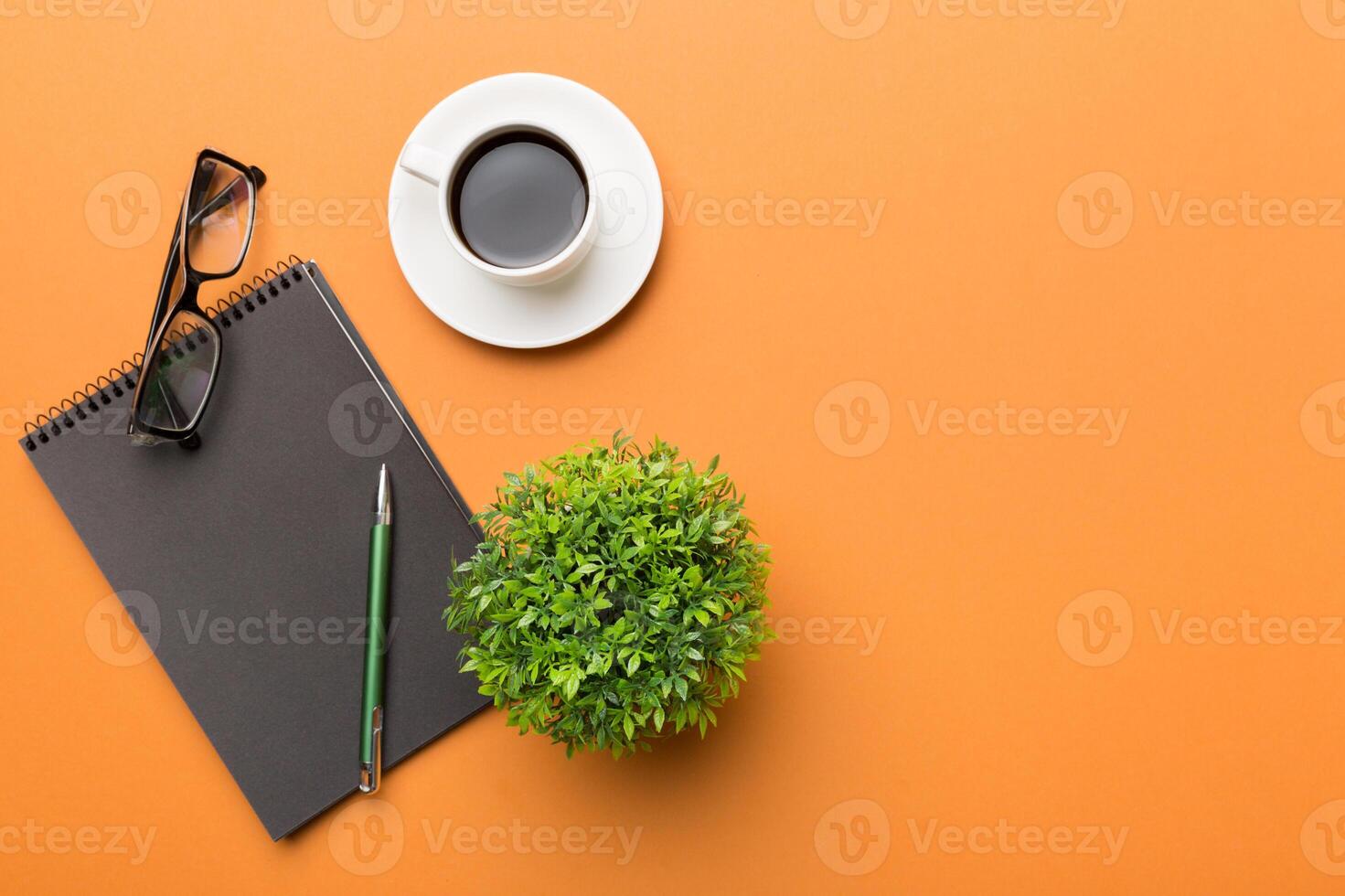 Modern office desk table with notebook and other supplies with cup of coffee. Blank notebook page for you design. Top view, flat lay photo