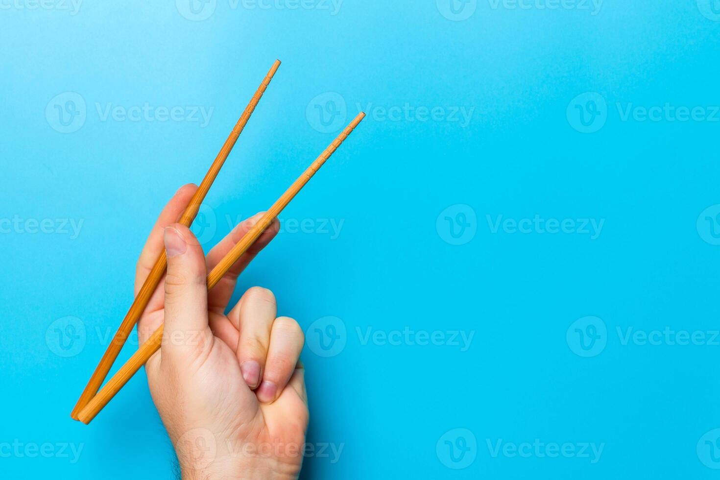 Wooden chopsticks in male hand on black background with empty space for your idea. Tasty food concept photo