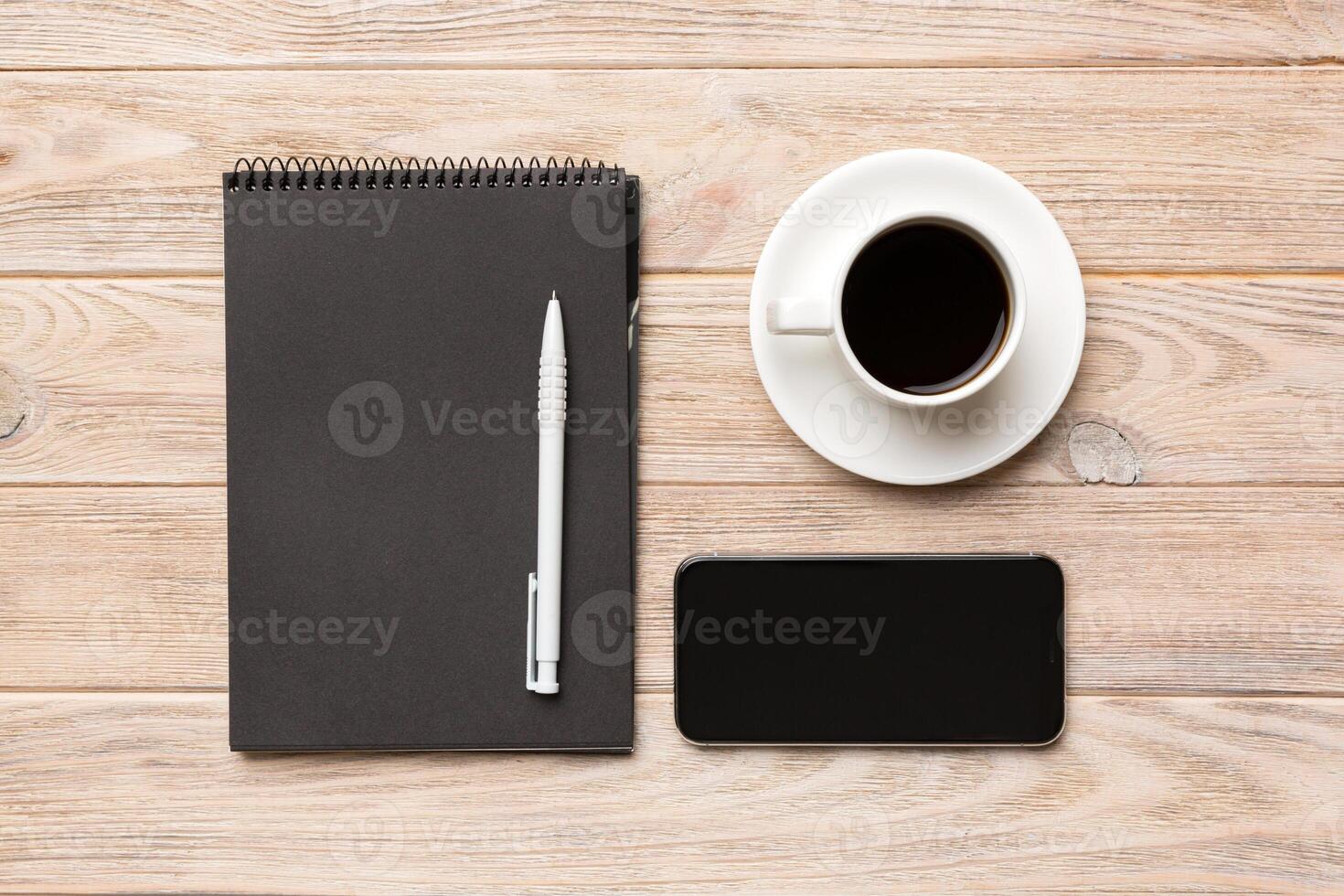 Modern office desk table with notebook, smartphone and other supplies with cup of coffee. Blank notebook page for you design. Top view, flat lay photo