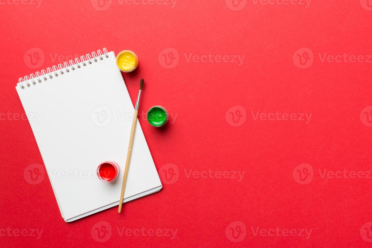 Album pages and paints, pencils, brush on a colored background. Top view with empty space. workplace for creativity. home teaching concept drawing photo