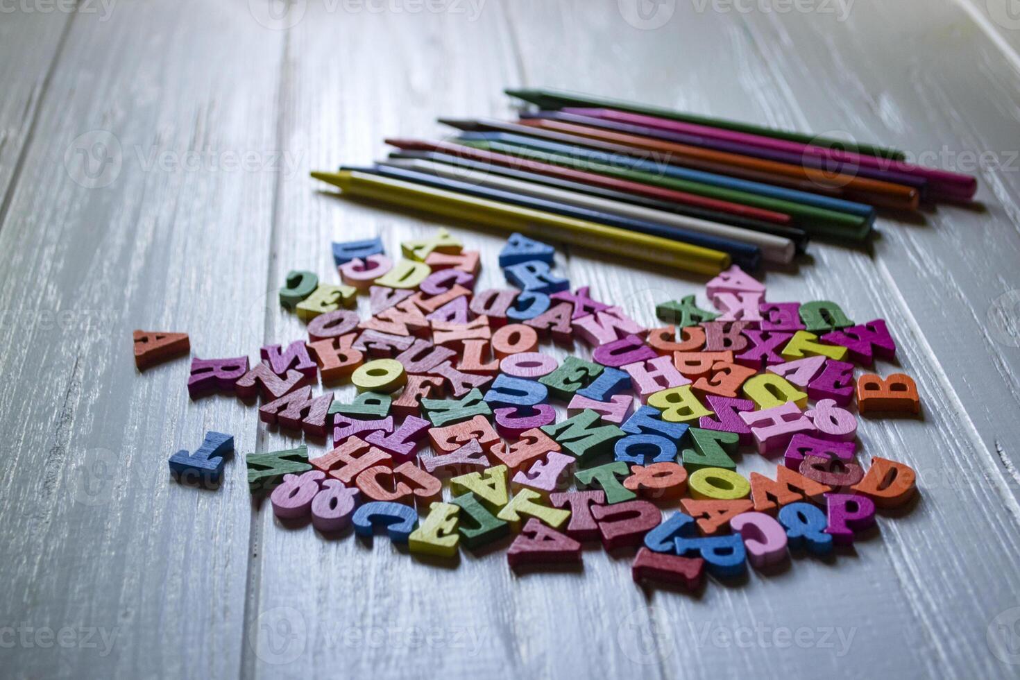 Multicolor letters and set of pencils on the table. Colorful wooden alphabet and pencils on a table. photo