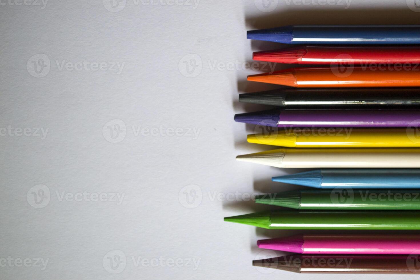 Multicolored pencils on white background. A palette of pencils on a table, close up. photo