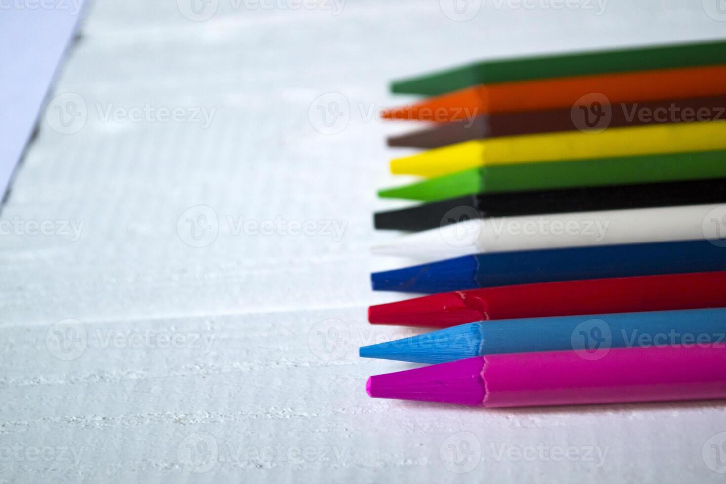 Multicolored pencils on white background. A palette of pencils on a table, close up. photo