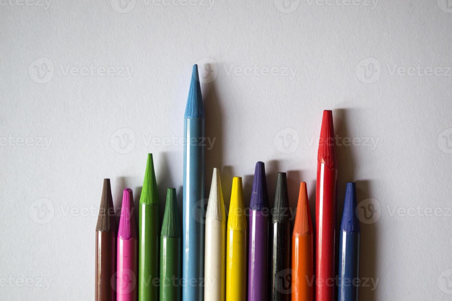 Multicolored pencils on white background. A palette of pencils on a table, close up. photo