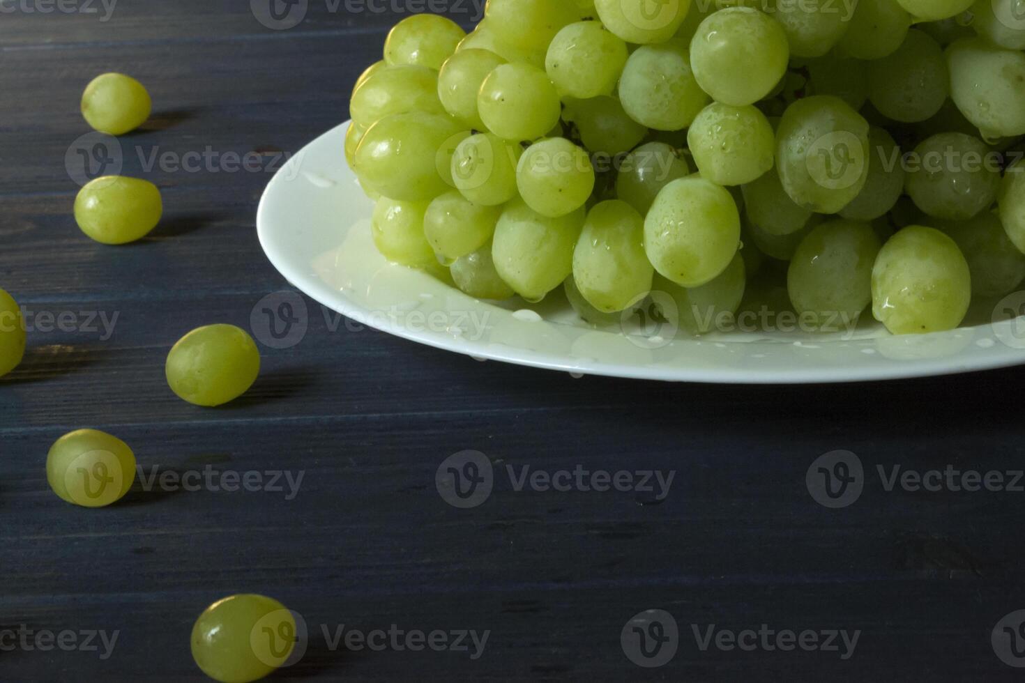 Ripe grapes in a plate on a dark blue wooden table. photo