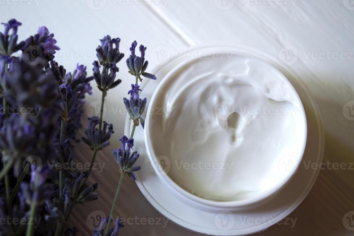 Lavender flowers, candles and cream on a white wooden background. Beauty care. Top view. photo