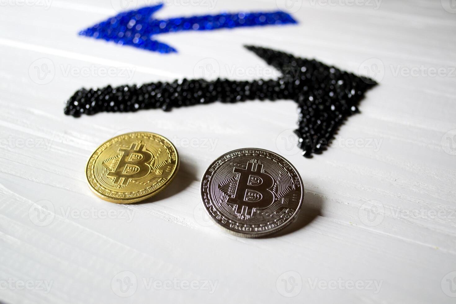 Golden and silver bitcoins with arrows up and down on a white wooden background. photo