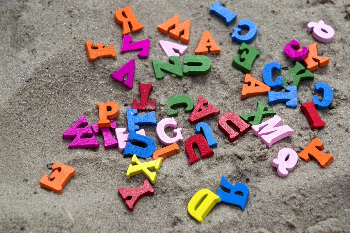 Multicolor wooden letters on a sand close up. photo