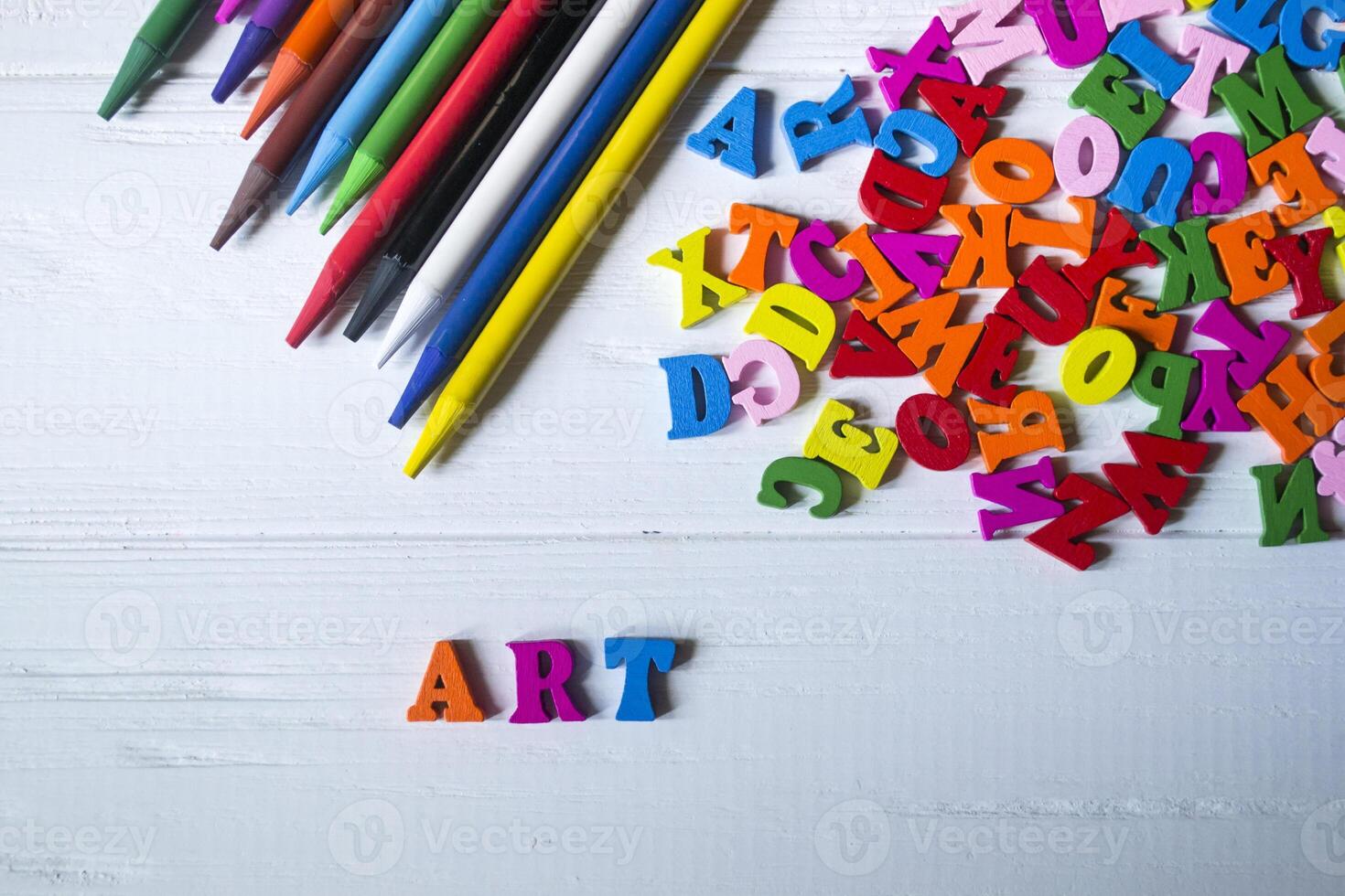 Multicolor letters and set of pencils on the table. Colorful wooden alphabet and pencils on a table. photo