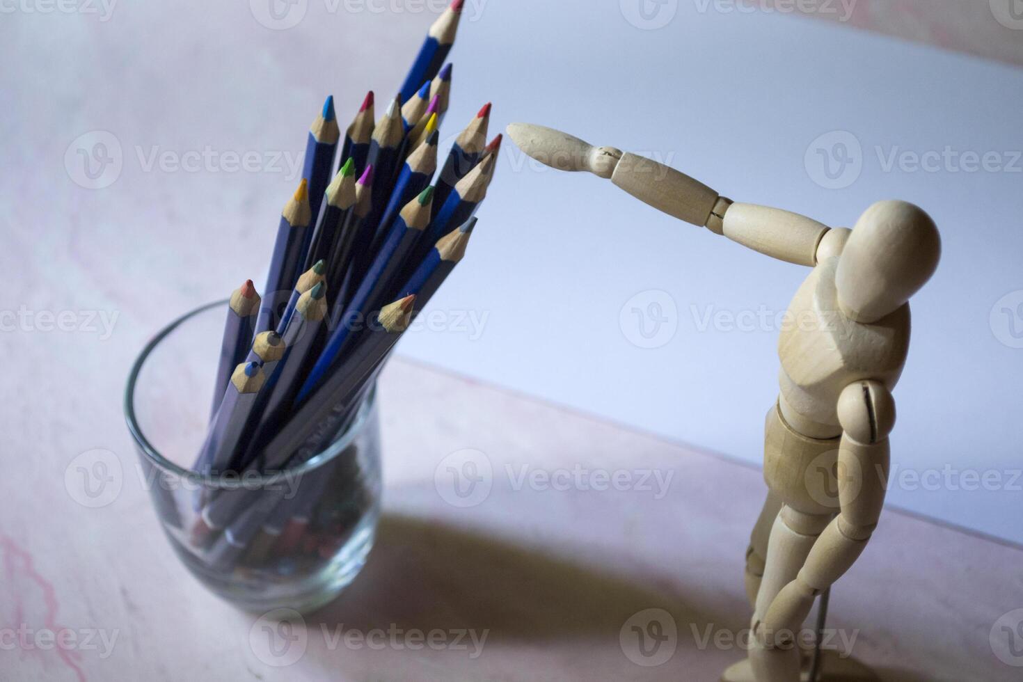 Colored pencils, empty paper and dummy for drawing on the table. photo