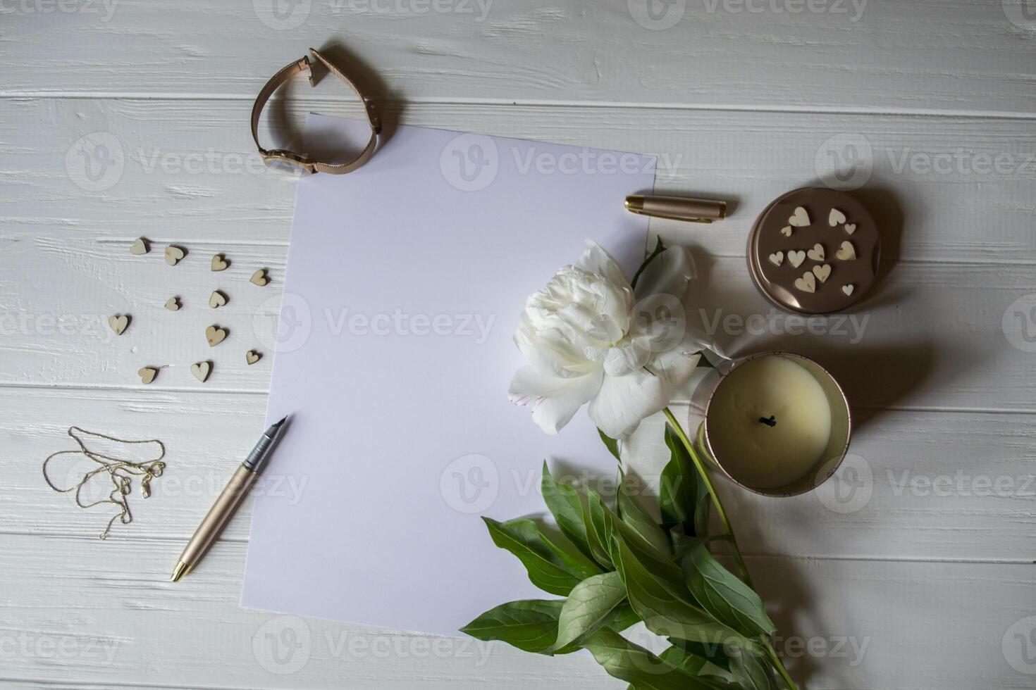 White paper, pen, peony and decor on the desk. Beautiful still life on the desktop. photo