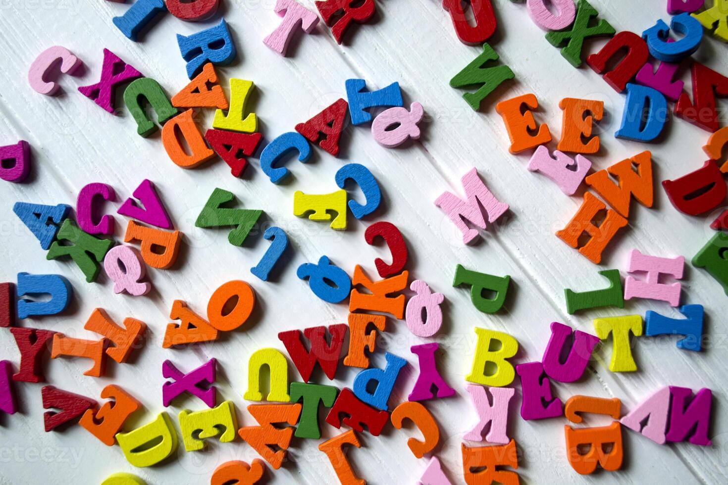 Multicolor letters on a white wooden background. Colorful wooden alphabet on a table. photo
