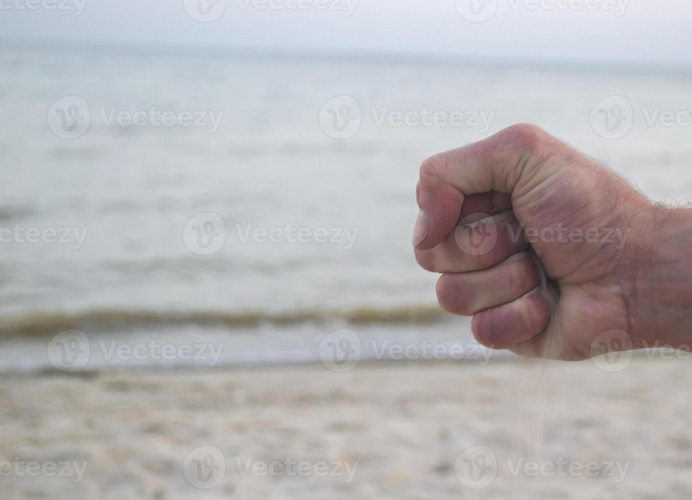 The sand is pouring from male hands. photo